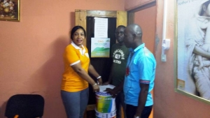 La pr&eacute;sidente de l'ONG, Tour&eacute; Massaty Konet, remet un pot de peinture &agrave; Traor&eacute; Issouf, conseiller du directeur du COM,